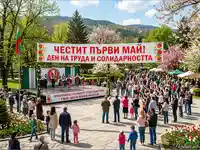 Празник на Първи май в България: Фолклорни танци, публика с флагове и пролетна атмосфера в парка.